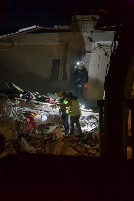 Rescue workers search for survivors in a collapsed building during the night. Urgent disaster response.