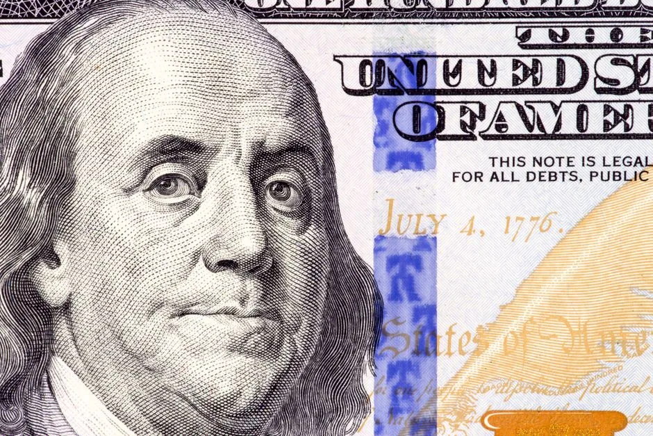 Detailed close-up of Benjamin Franklin's portrait on a 100 dollar bill showing July 4, 1776.