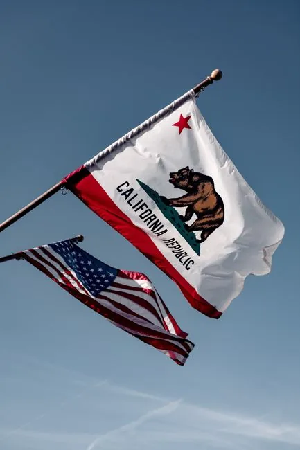 California and US flags waving against a clear blue sky in Santa Barbara, embodying American patriotism.