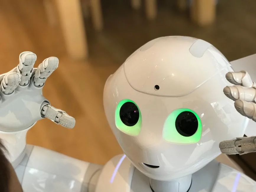 A futuristic humanoid robot with glowing green eyes in a modern setting.