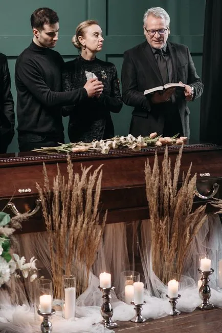 A heartfelt funeral ceremony with family gathered around a coffin adorned with flowers and lit candles.