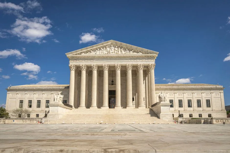 The majestic facade of the United States Supreme Court under a clear blue sky.