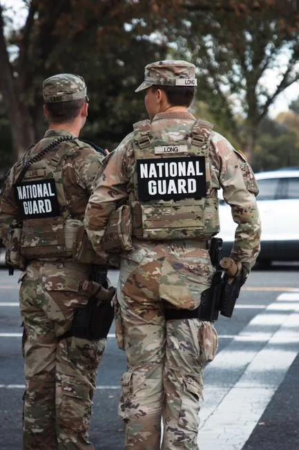 Two National Guard soldiers in uniform standing outdoors on a city street.