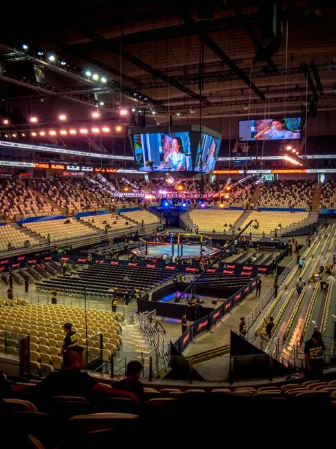 A vibrant empty arena prepping for a major sporting event, showcasing colorful lights and screens.