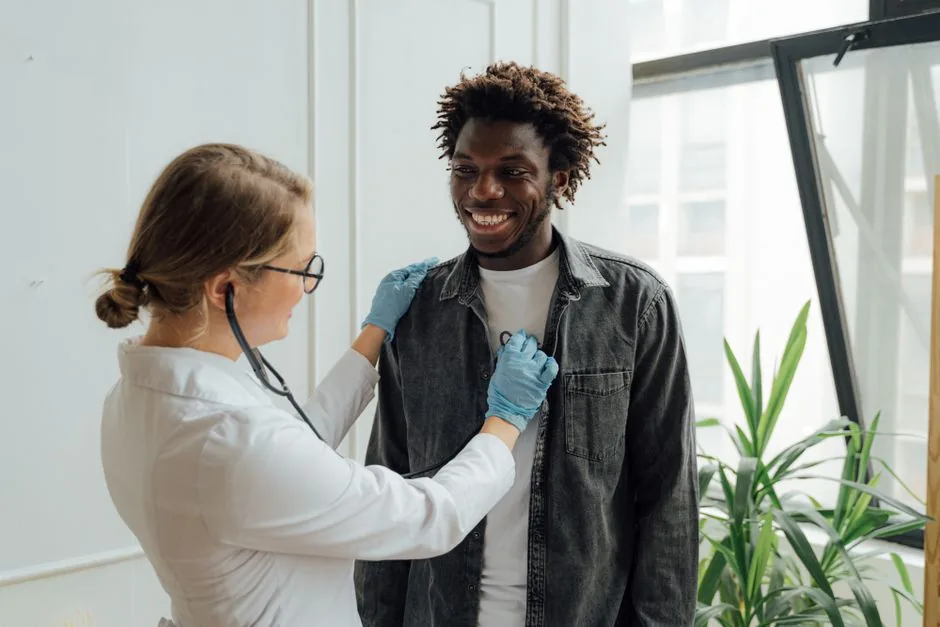 Doctor with stethoscope examining a smiling patient indoors, promoting health and care.