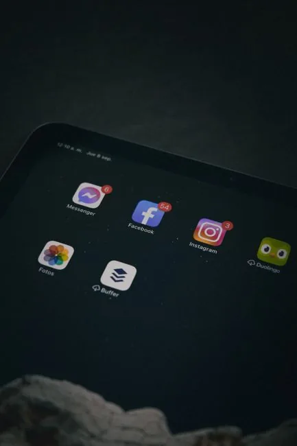 Close-up of a tablet screen displaying social media apps in a dim setting.