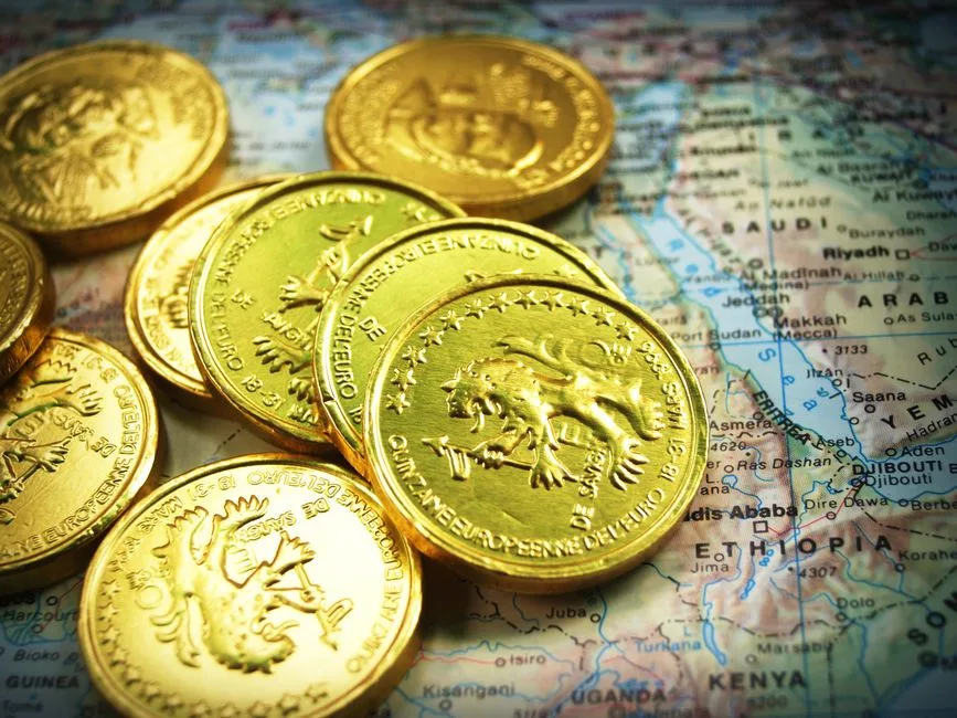 Stack of shiny gold coins placed on a world map, symbolizing global wealth.