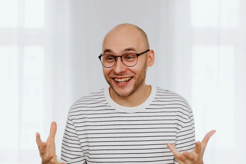 Smiling bald man with a striped shirt displaying happiness indoors.