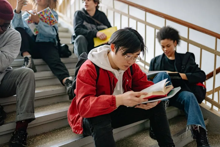 A diverse group of students sitting on a staircase, reading and studying together.