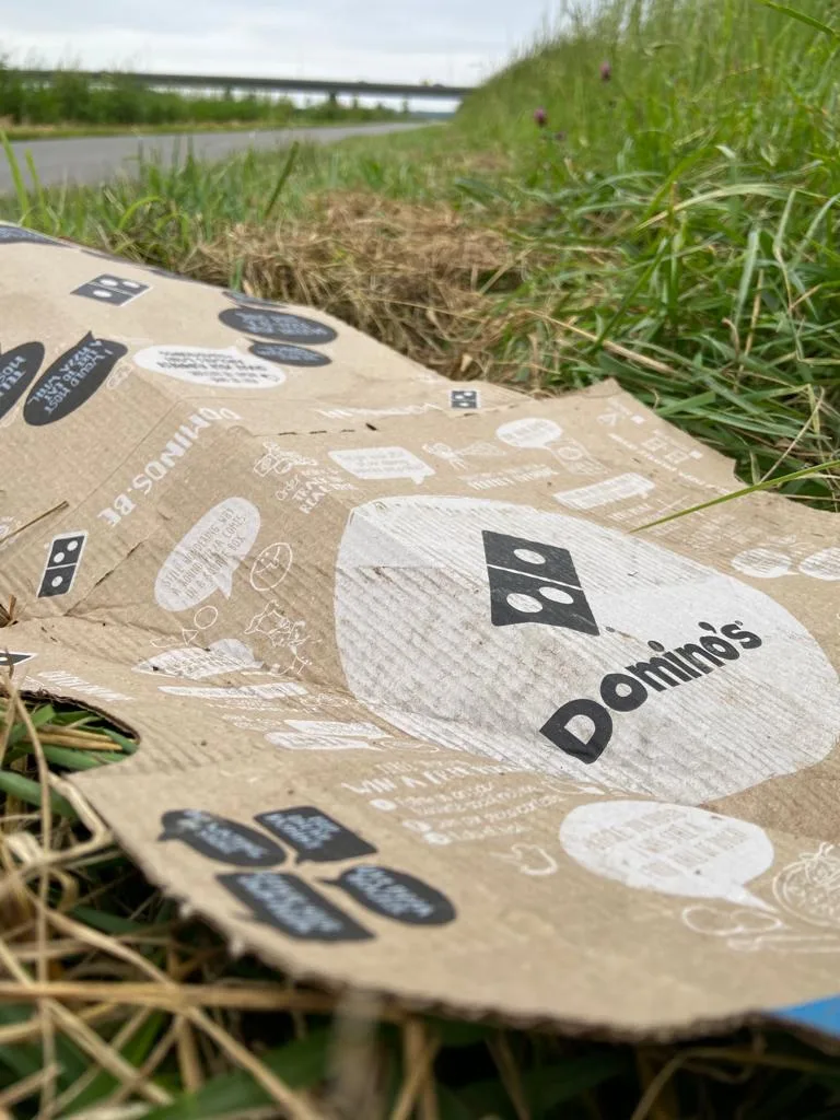 Een pizzadoos van Domino's ligt langs een landweg bij Wilp. Uit onderzoek blijkt dat pizzadozen van deze fastfoodketen PFAS bevatten.