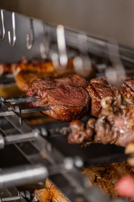 Close-up of juicy grilled meat skewered on a rotisserie, highlighting the perfect grill marks and savory texture.
