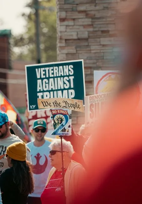 A diverse group of protesters at a rally, displaying political signs and expressing their views.