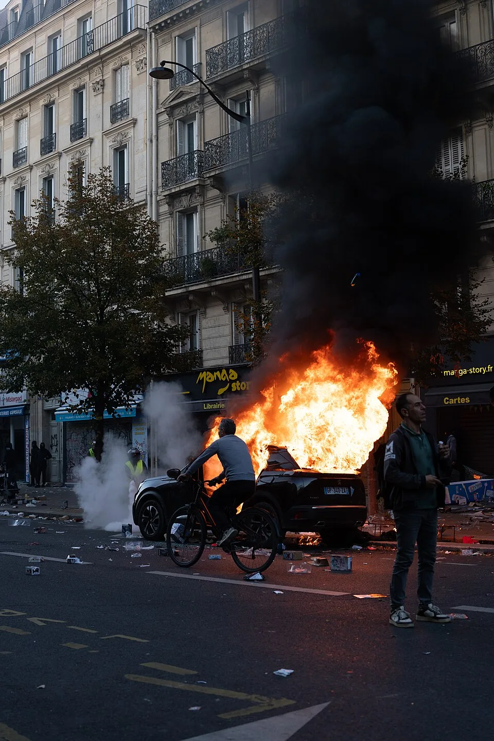Paris riots, 17 October 2026 - Burning car and passing cyclist - JJxFile 0025