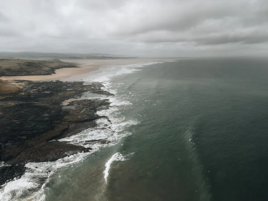 Scenic aerial view of the Northumberland coastline with rocky seacoast and waves.