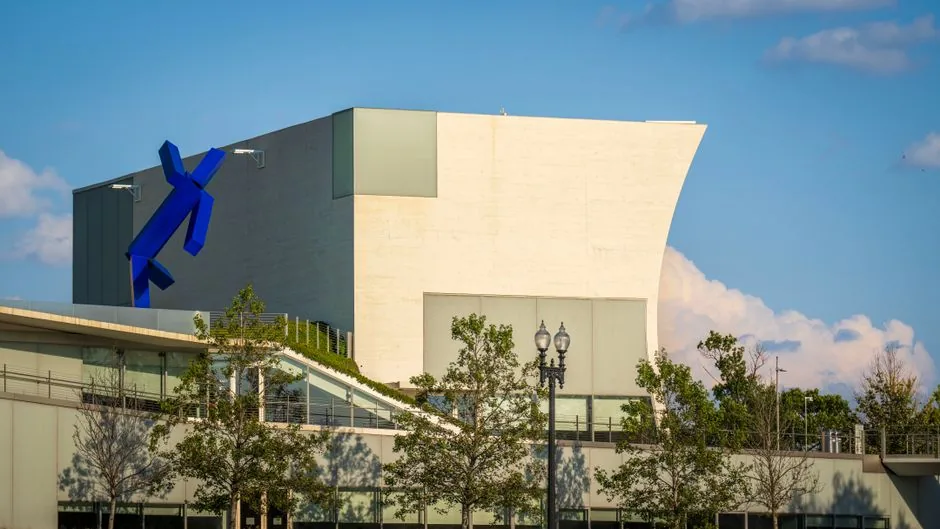 A modern architectural building with a striking blue sculpture set against a clear sky.